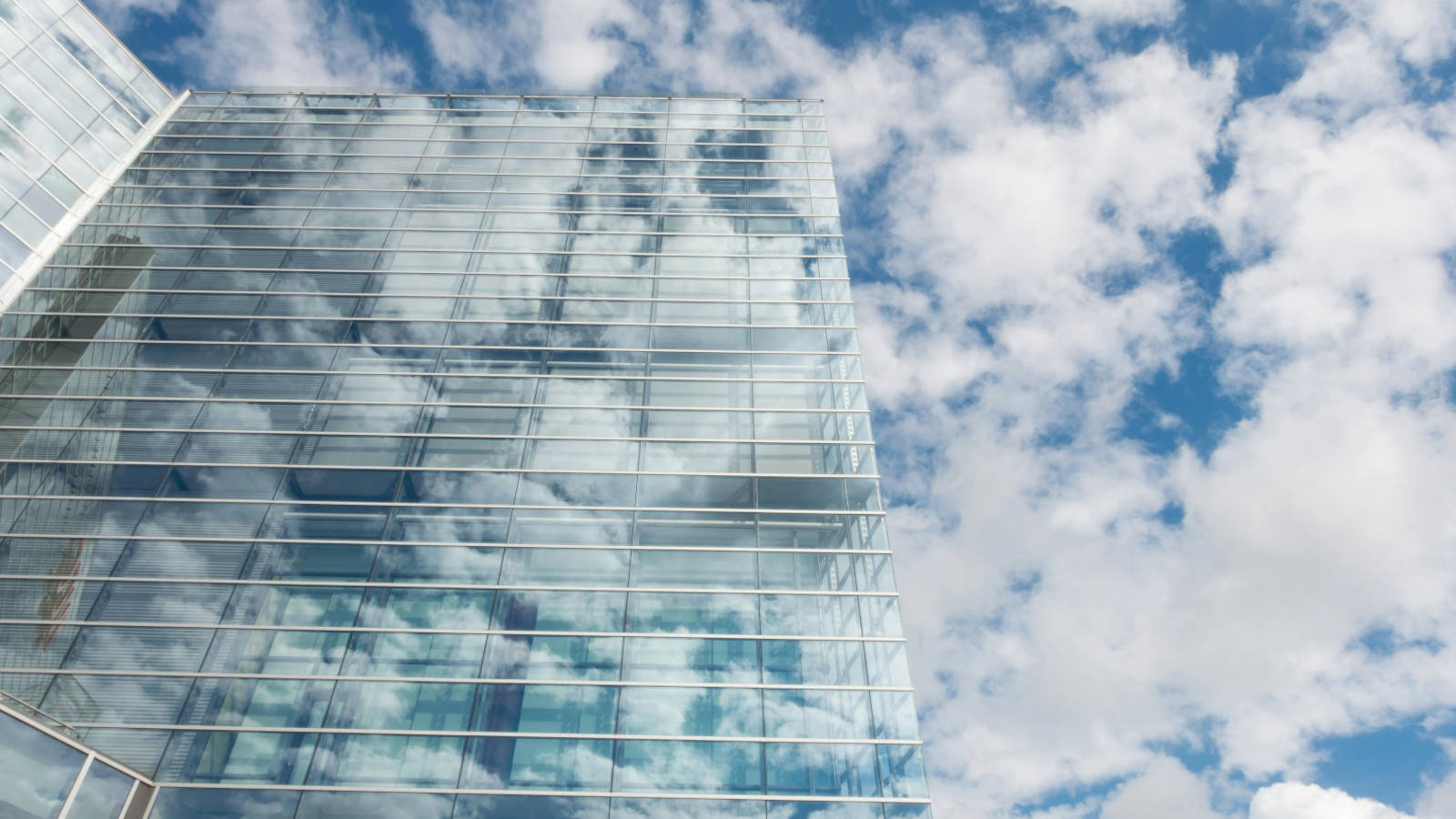 Moderne Glasfassade eines Gebäudes, in der sich der Himmel spiegelt